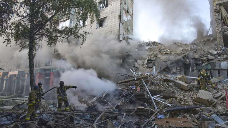 Bombeiros trabalham nos escombros de um prédio derrubado por um dos bombardeios russos contra Kiev nesta terça-feira, 17 de junho de 2025.
