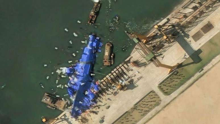 Imagens de satélite mostram uma aparente tentativa de ocultar o navio de guerra norte-coreano, que virou ao ser lançado ao mar de lado a partir do cais