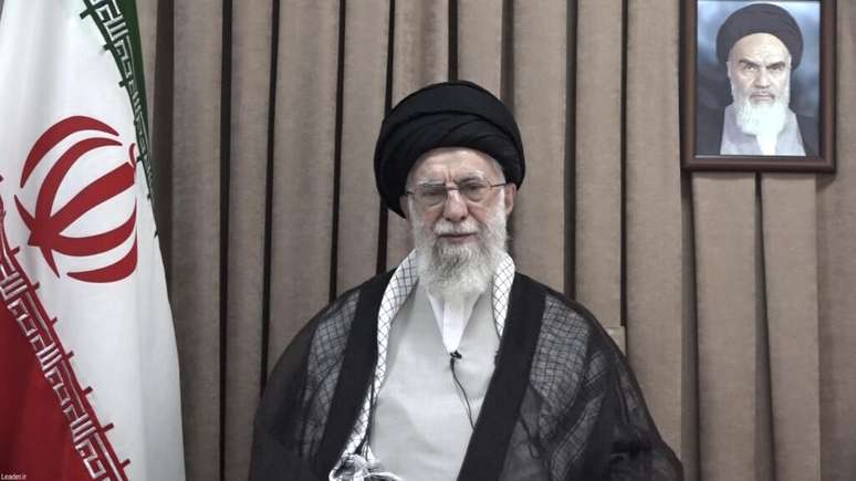 Foto divulgada na quarta-feira,18 de junho de 2025, pelo site oficial do gabinete do líder supremo iraniano, mostra o Líder Supremo, Aiatolá Ali Khamenei, em um discurso televisionado, sob um retrato do falecido fundador revolucionário, Aiatolá Khomeini. (Gabinete do Líder Supremo Iraniano via AP)