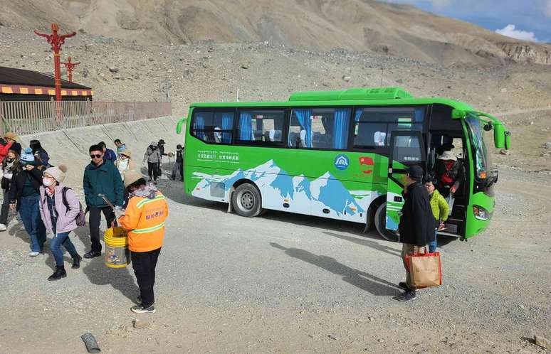Os turistas saem de um ônibus elétrico verde.