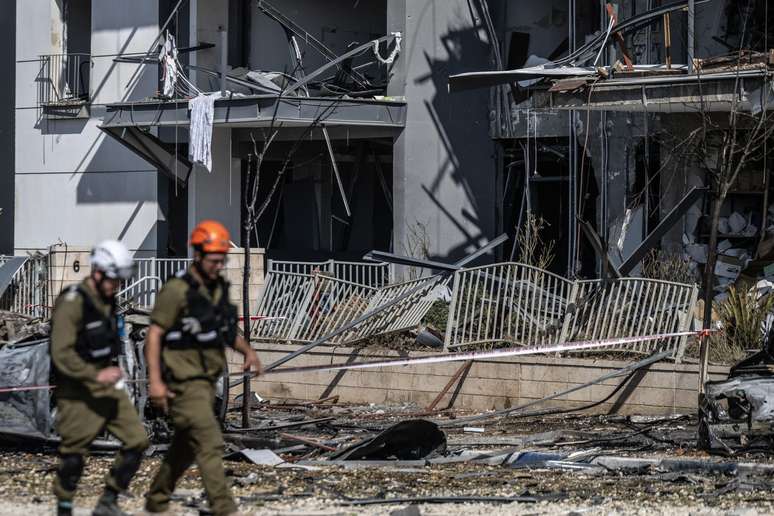 Policiais israelenses e especialistas em desarmamento de bombas são vistos trabalhando no local do impacto após um míssil supostamente lançado do Irã atingir a cidade de Bersheba, no sul de Israel, em 20 de junho de 2025. As autoridades iniciaram investigações após o incidente como parte de medidas de segurança mais amplas em meio às tensões regionais em curso.