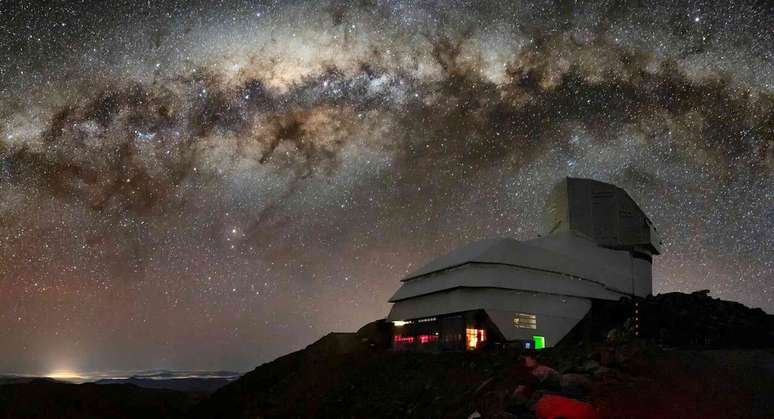 Um observatório, que parece um edifício com uma cúpula no topo, na encosta de uma montanha, com um céu estrelado ao fundo.