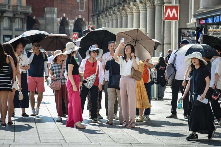 Turistas se protegem contra calor no centro de Milão, na Itália