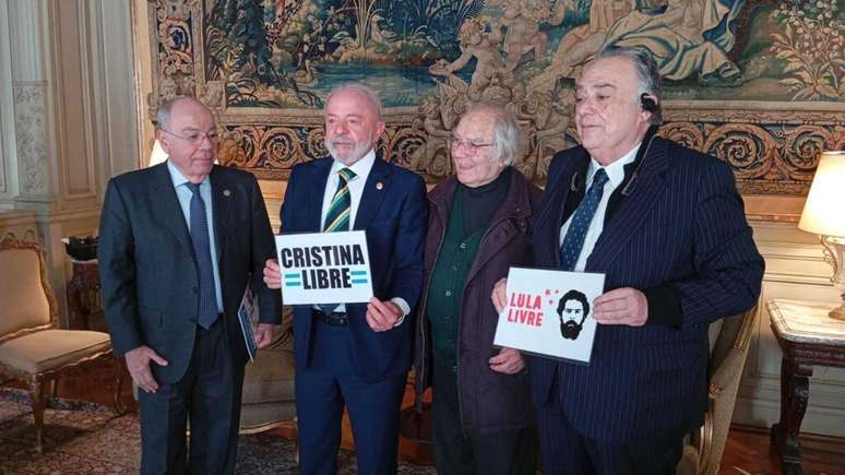 O presidente Lula segura cartaz da campanha 'Cristina Libre' ao lado do chanceler Mauro Vieira (à esq.) e o prêmio Nobel da Paz, Adolfo Pérez Esquivel. O deputado Eduardo Valdés (à dir.) exibe o cartaz Lula Livre. 03/07/2025