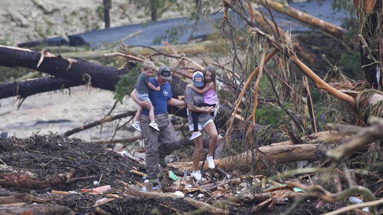 Pessoas caminham em meio aos escombros de uma ponte no rio Guadalupe, que transbordou após fortes chuvas, causando mortes e destruição. Em 5 de julho de 2025, no Texas.