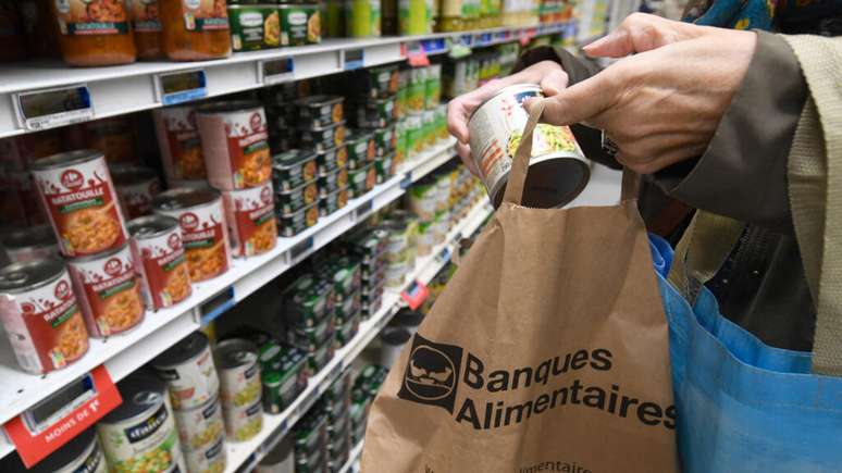 Um cliente coloca um item em uma sacola do "Banco de Alimentos".
