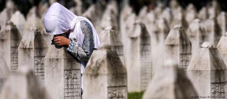 Uma mulher bósnia chora no túmulo de um parente que foi assassinado no genocídio de Srebrenica