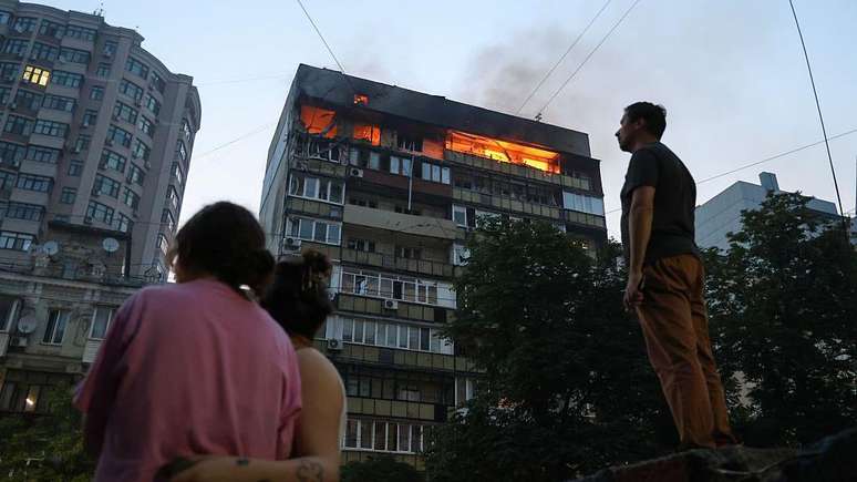 Morador de Kiev observa incêndio em prédio após ataque: bombardeios têm se intensificado