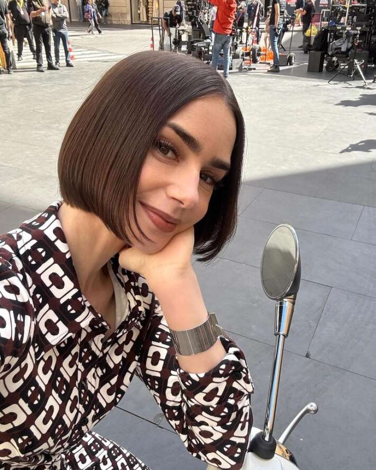 Lilly Collins, que interpreta a protagonista de 'Emily in Paris', sentada em uma vespa em imagem divulgada pela Netflix