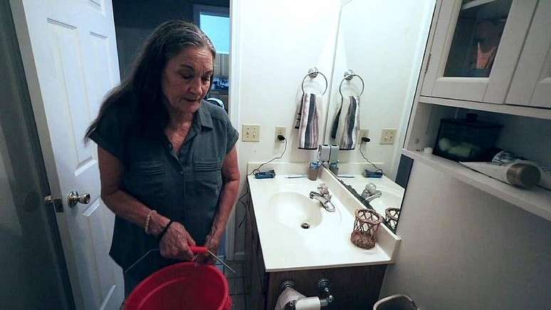 Beverly Morris precisa encher baldes para usar o banheiro devido à baixa pressão da água.