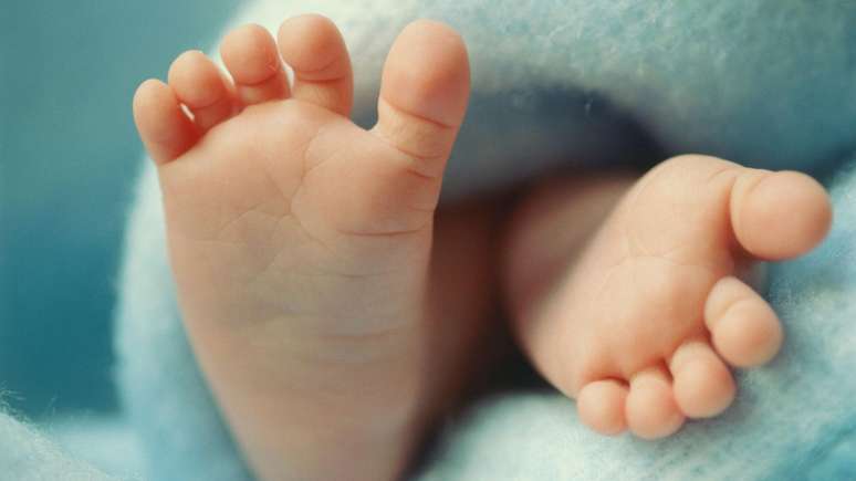 Imagem fechada dos pés de um bebê envolto em cobertor azul