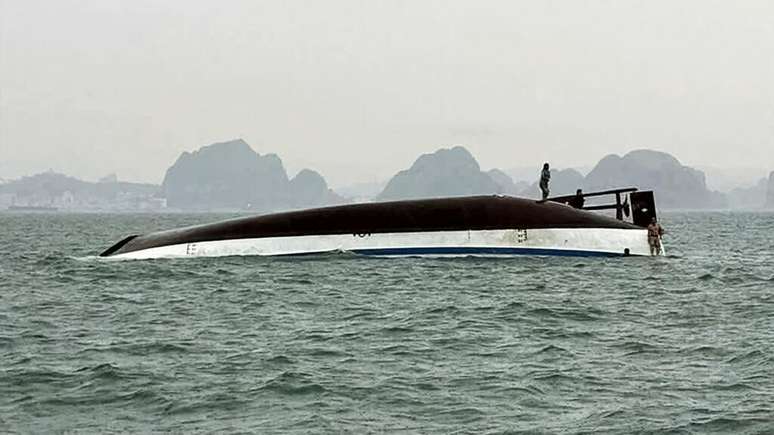 Um homem se equilibra sobre o casco do Wonder Sea, embarcação turística que naufragou em 19 de julho de 2025 na baía de Halong, no Vietnã. A tragédia deixou ao menos 34 mortos e vários desaparecidos.