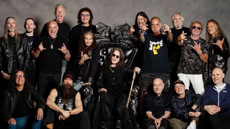 Ozzy Osbourne em seu trono preto, ladeado por 16 m&uacute;sicos do line-up, em foto tirada antes do show