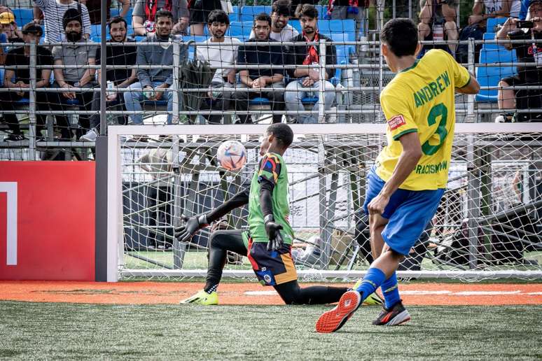 Jogador brasileiro bate pênalti na edição de 2024 da Homeless World Cup. Goleiro joga em pé e agachado, dependendo da situação.