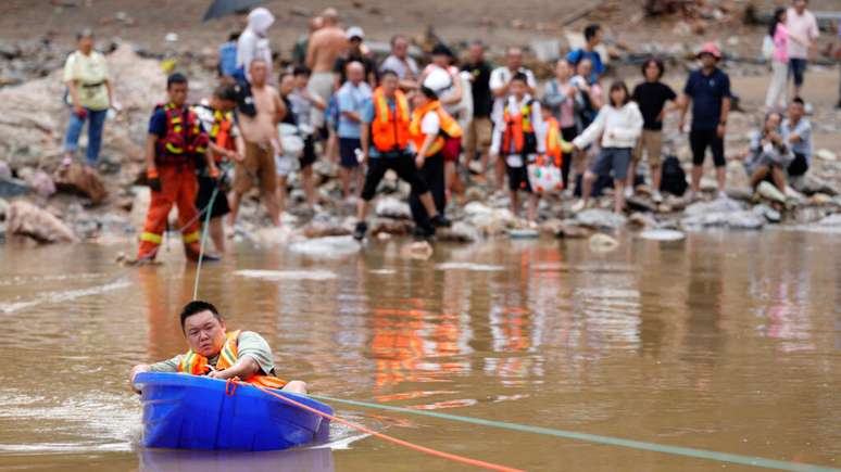 Moradores sendo socorridos após chuvas torrenciais nos arredores de Pequim.