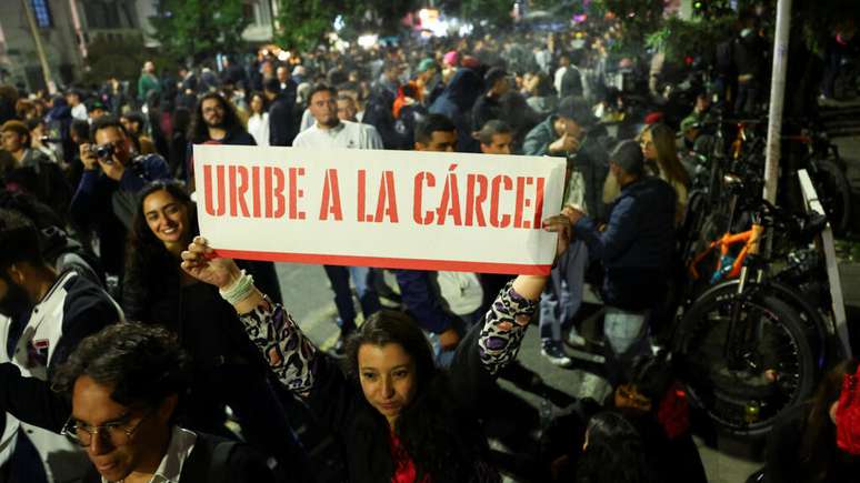 "Uribe na prisão", diz cartaz exibido por uma manifestante em Bogotá, durante protesto contra o ex-presidente Álvaro Uribe, em 28 de julho de 2025.
