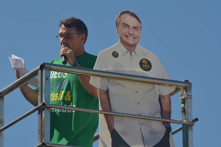 Flávio Bolsonaro discursa ao lado de papelão do pai