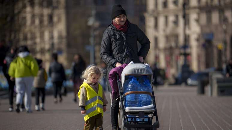 Foto ilustrativa de uma mulher andando com uma criança na Praça da Independência de Kiev.