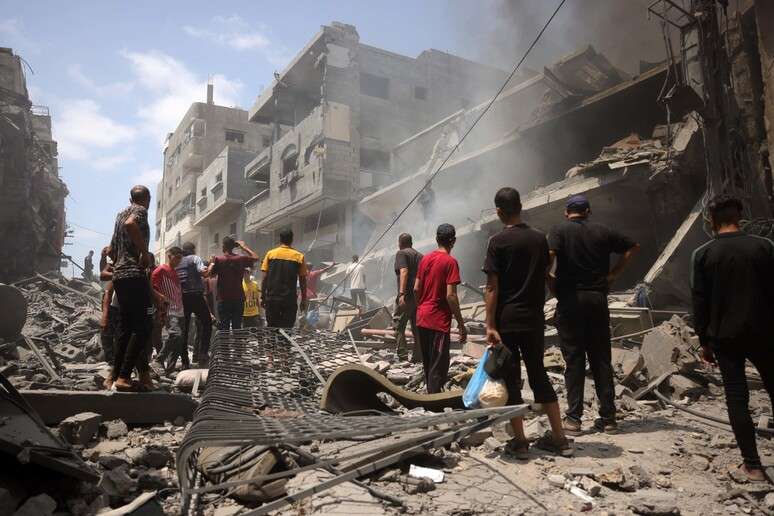 Palestinos caminham em meio a escombros na Cidade de Gaza