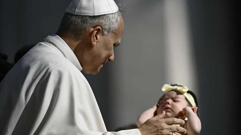 Em 100 dias de papado, Leão XIV ainda não formou sua equipe e nem nomeou seu sucessor à frente do Dicastério para os Bispos, o que tem gerado muitas especulações e críticas, afirma uma reportagem do jornal francês Libération desta terça-feira (12). Na foto, o papa abençoa um bebê na Praça de São Pedro, no Vaticano, em 6 de agosto de 2025.