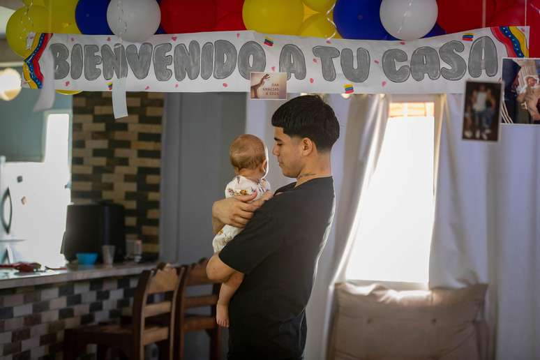 Jo&eacute;n Su&aacute;rez segura a filha no colo na casa da fam&iacute;lia nos arredores de Caracas