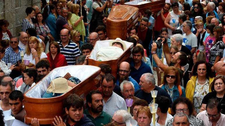Pessoas levam nos ombros caix&otilde;es com pessoas vivas no seu interior, durante a prociss&atilde;o de Santa Marta de Ribarteme, em 2019