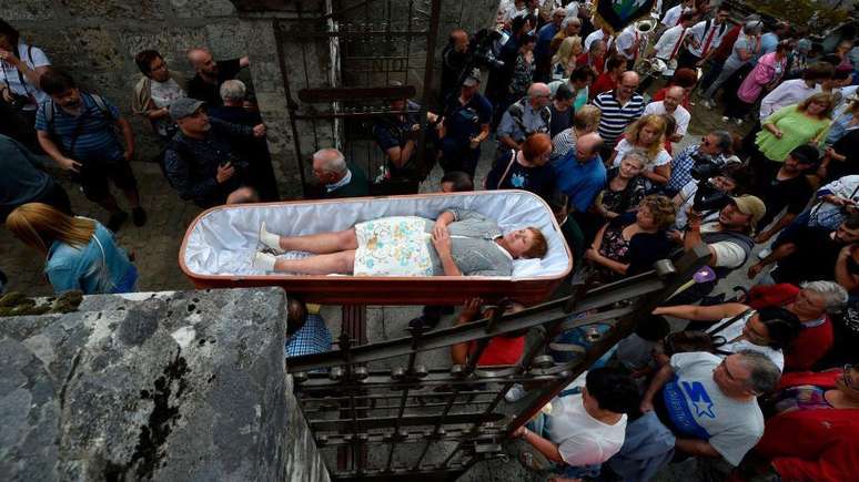 Mulher sendo levada em um caix&atilde;o aberto durante a romaria