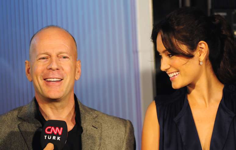Bruce Willis concedendo entrevista enquanto sua esposa sorri