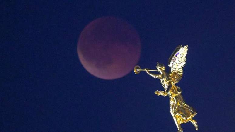 Uma est&aacute;tua dourada em Dresden, Alemanha, &eacute; vista ao lado da Lua