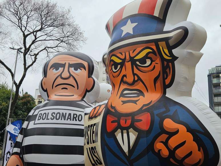 Em S&atilde;o Paulo, Bonecos infl&aacute;veis de Jair Bolsonaro, vestindo roupa de presidi&aacute;rio, e de Donald Trump, segurando um cartaz onde se l&ecirc; 'Epstein list', numa refer&ecirc;ncia aos arquivos do caso envolvendo o falecido agressor sexual Jeffrey Epstein