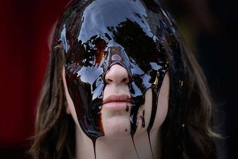 Mulher jovem com os olhos cobertos por &oacute;leo escuro