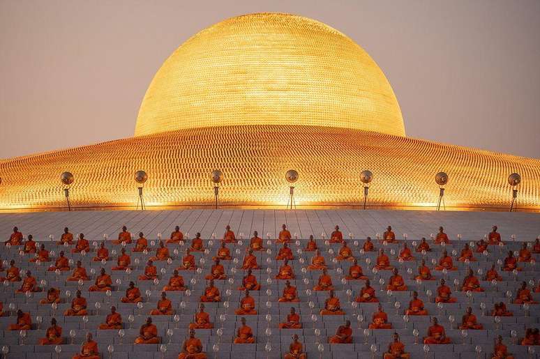Monges rezando em frente &agrave; c&uacute;pula dourada do templo Wat Phra Dhammakaya, na Tail&acirc;ndia