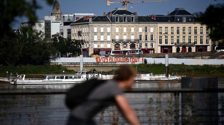 Ciclista diante de grafite com os dizeres "10 septembre, bloquons tout" ("10 de setembro, vamos bloquear tudo"), na cidade de Bordeaux. Imagem de 25 de agosto de 2025.