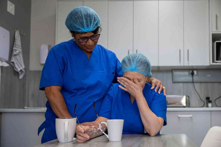 Dois profissionais de sa&uacute;de se consolam mutuamente em um momento de estresse emocional