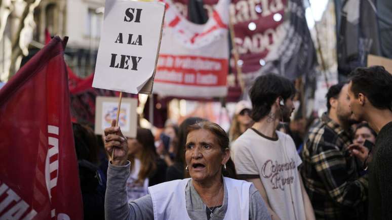 Uma manifestante contra o governo segura um cartaz com a frase 'Sim à lei', enquanto marcha contra o veto do presidente Javier Milei a projetos que aumentariam o financiamento de um hospital pediátrico e de várias universidades em Buenos Aires, Argentina, na sexta-feira, 12 de setembro de 2025.