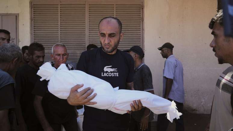 Homem carrega corpo de criança de três anos morta em bombardeio israelense em Deir al-Balah, na Faixa de Gaza, em 14 de setembro de 2025.