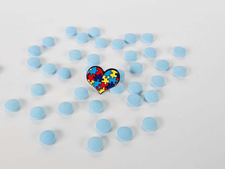 Ilustra&ccedil;&atilde;o com comprimidos e sobre uma mesa com pequeno cora&ccedil;&atilde;o formado por pe&ccedil;as de um quebra-cabe&ccedil;as colorido