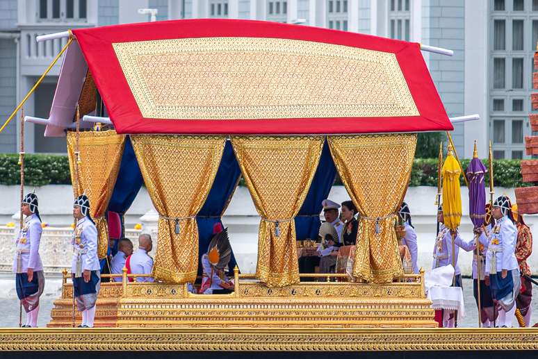 O rei Maha Vajiralongkorn e a rainha Suthida Tidjai sentam-se em sua barca&ccedil;a real pelo Rio Chao Phraya durante a Prociss&atilde;o da Barca&ccedil;a Real em Bangkok