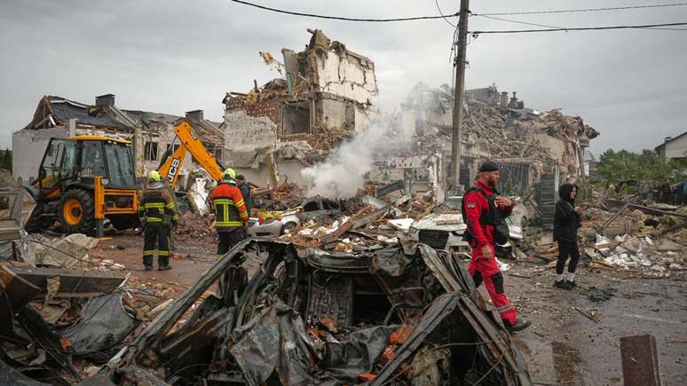 Equipes de resgate trabalham nos escombros de um prédio atingido por ataques russos em Kiev neste domingo, 28 de setembro de 2025.