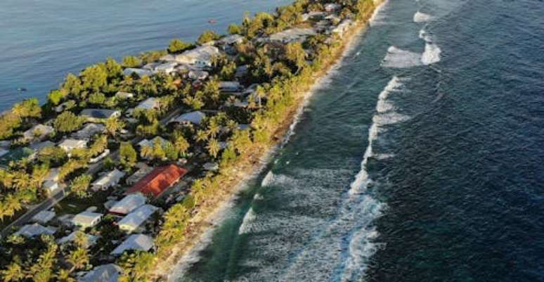 Como consequência do aquecimento global previsto pelos modelos há mais de 50 anos, a nação insular de Tuvalu está perdendo terras devido ao aumento do nível do mar, e suas fazendas e suprimentos de água estão ameaçados pela água salgada. Mario Tama/Getty Images