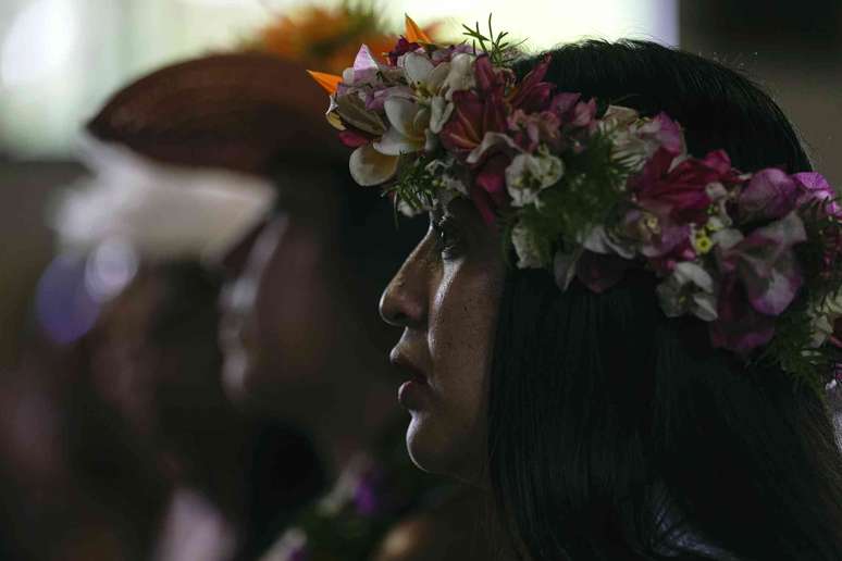 Close-up de fotos de uma fileira de pessoas usando cocares florais em uma sala escura