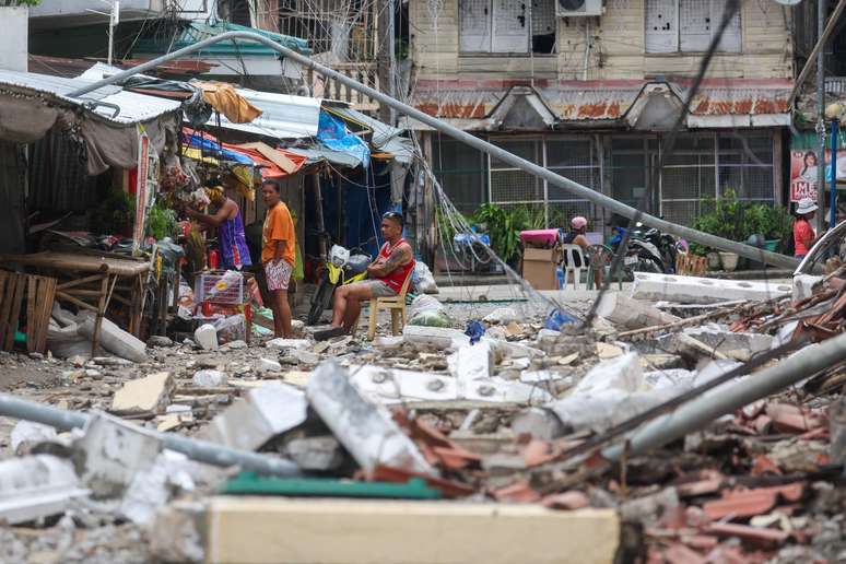 Moradores locais permanecem nas ruas perto dos escombros de prédios danificados em meio a tremores secundários frequentes, após um terremoto de magnitude 6,9 ​​que sacudiu partes da ilha, na Cidade de Bogo, Cebu, Filipinas.