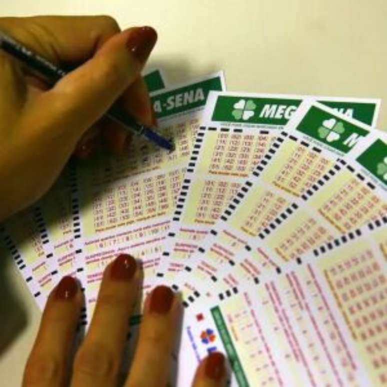 Mulher marcando números em talões da Mega-Sena.