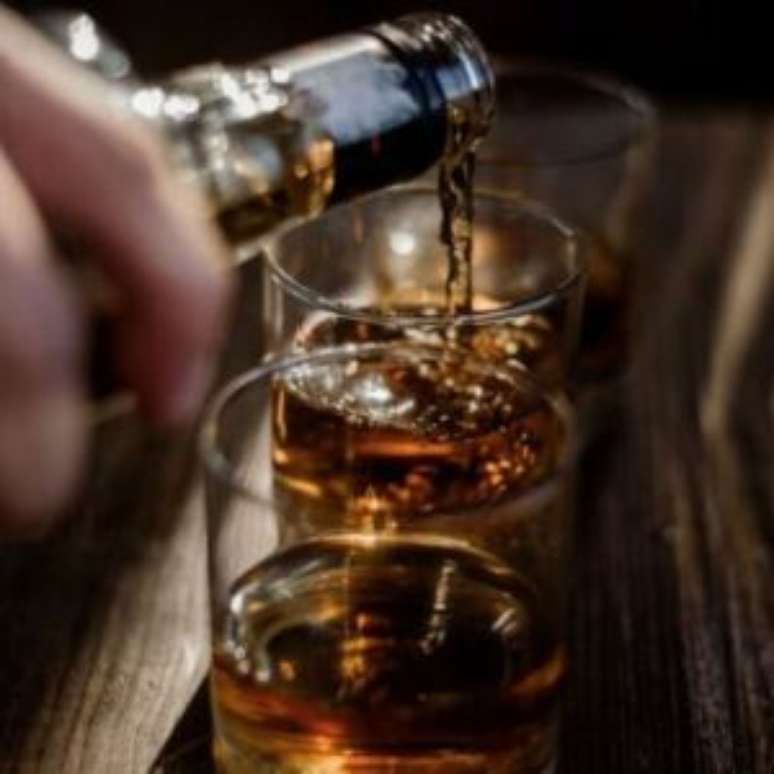 Pessoa colocando bebida alcoólica em copos.