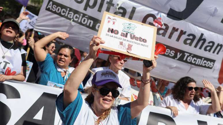 Uma mulher segura um cartaz com os dizeres “Não ao veto” enquanto pessoas protestam do lado de fora do Congresso Nacional e senadores debatem dentro do prédio os vetos do presidente Javier Milei à lei de financiamento universitário e à lei de emergência para hospitais pediátricos, alegando esforços para controlar os gastos públicos, em Buenos Aires, Argentina, na manhã de 2 de outubro de 2025.