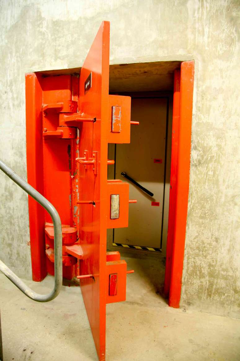 Uma porta met&aacute;lica vermelha &agrave; prova de explos&otilde;es em um bunker.