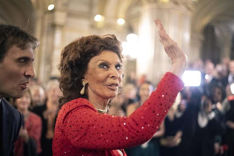 Atriz italiana estava sorridente e vestindo uma roupa vermelha