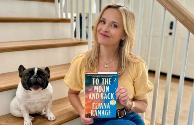 Reese Witherspoon com um dos livros selecionados para o seu Clube do Livro