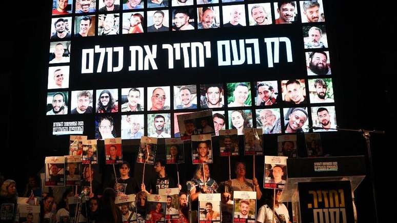 Pessoas seguram fotos de reféns israelenses enquanto se reúnem na "Praça dos Reféns" em Tel Aviv, para comemorar o acordo assinado entre Israel e o Hamas para uma troca de reféns por prisioneiros, baseada em um plano de 20 pontos proposto pelo presidente norte-americano Donald Trump, em 11 de outubro de 2025.