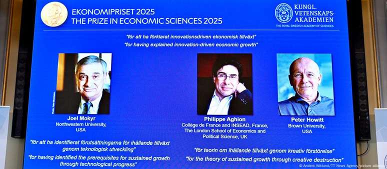 Retratos de Mokyr, Aghion e Howitt em telão durante anúncio do Prêmio Nobel de Economia 2025